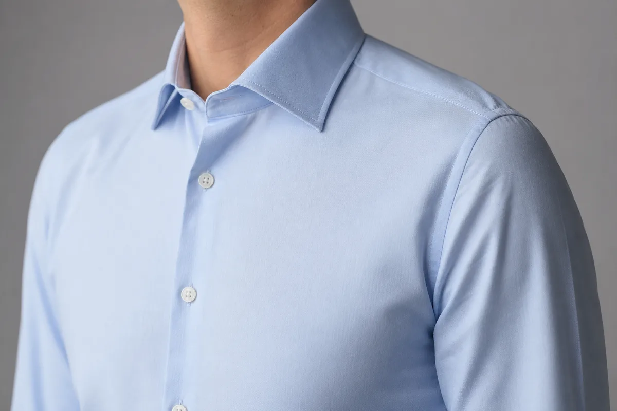 Chemise unie devant un fond gris uni, plan de détail sur un col sans motif
